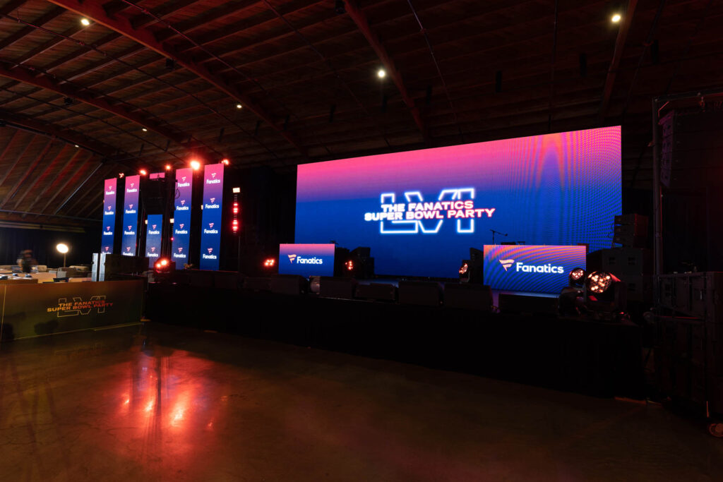 A large stage setup with bright LED screens displaying 