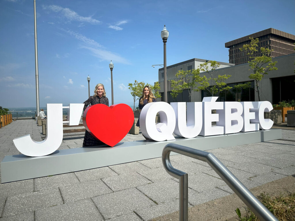 Two women stand behind a large sign that reads 